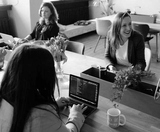 Lady smiling while at a desk with her co-workers.