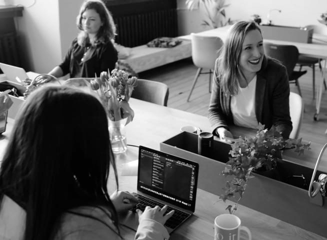 Lady smiling while at a desk with her co-workers.